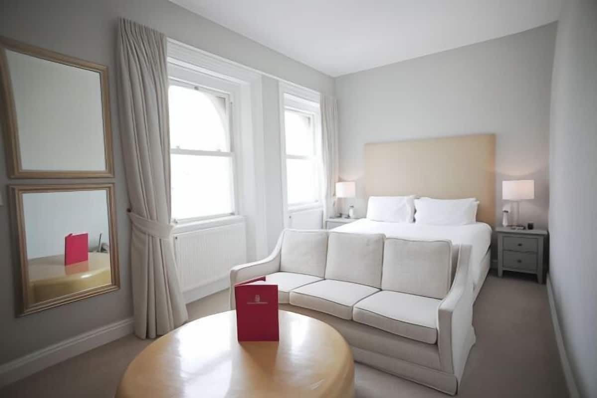 A hotel room with a bed, a sofa, a table, and a nightstand.