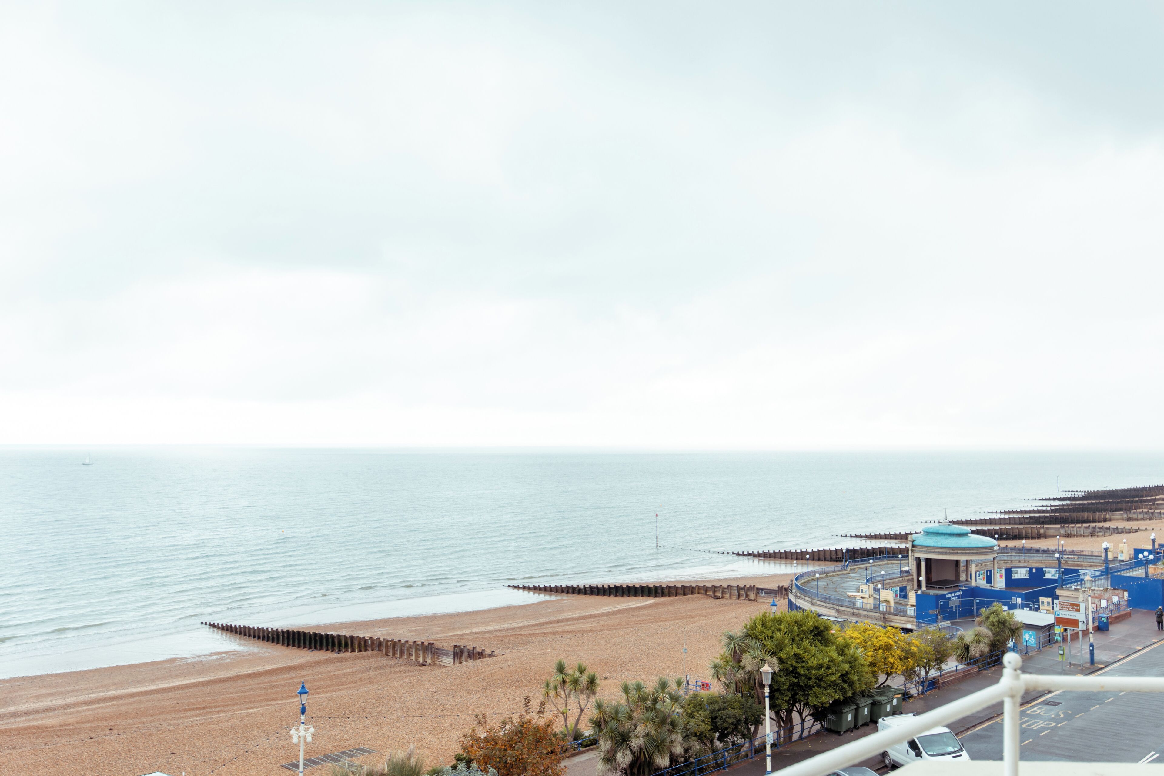 A coastal view with a beach, promenade, and a blue building with a dome roof.