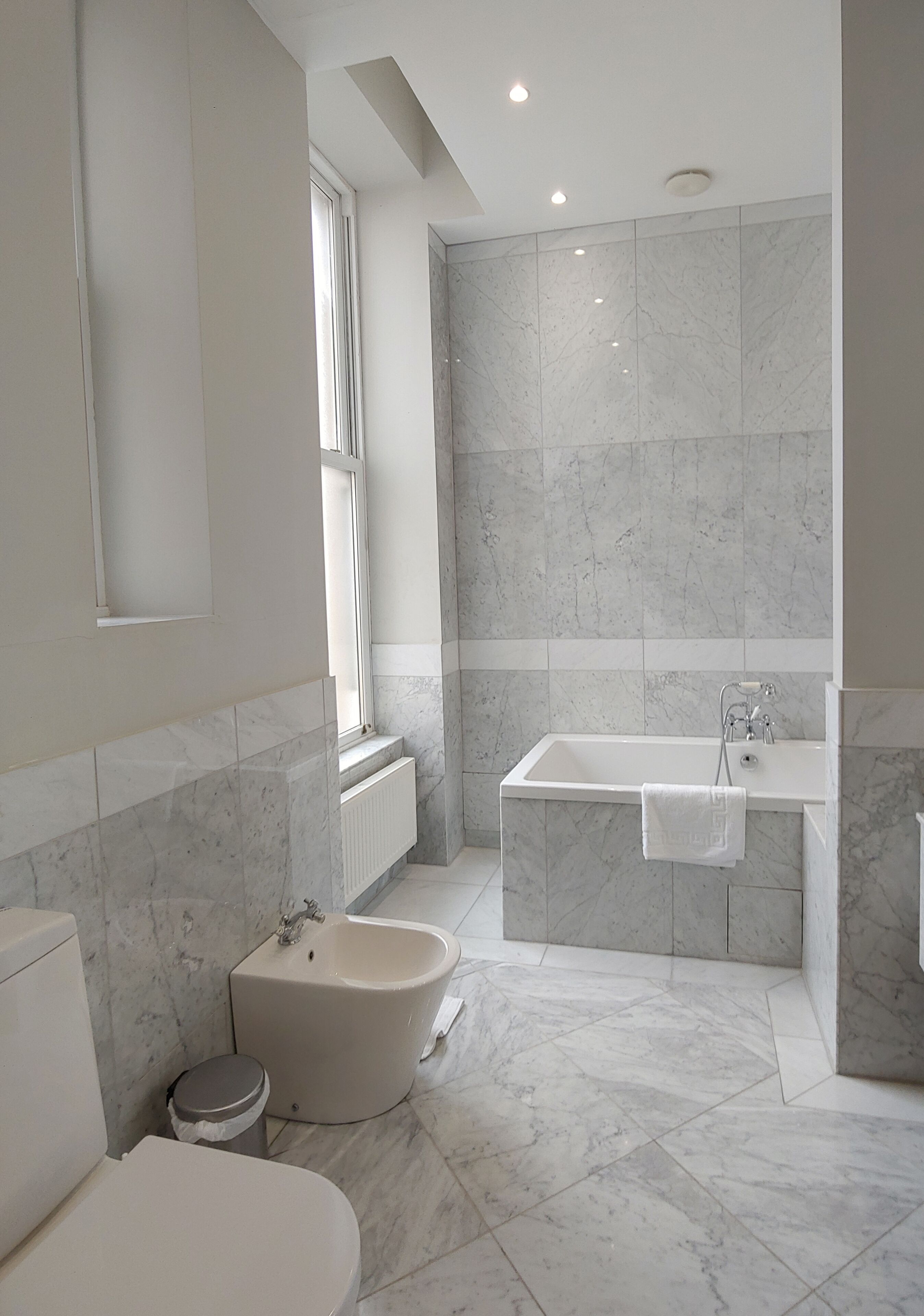 A modern bathroom with a bathtub, a bidet, and a toilet.