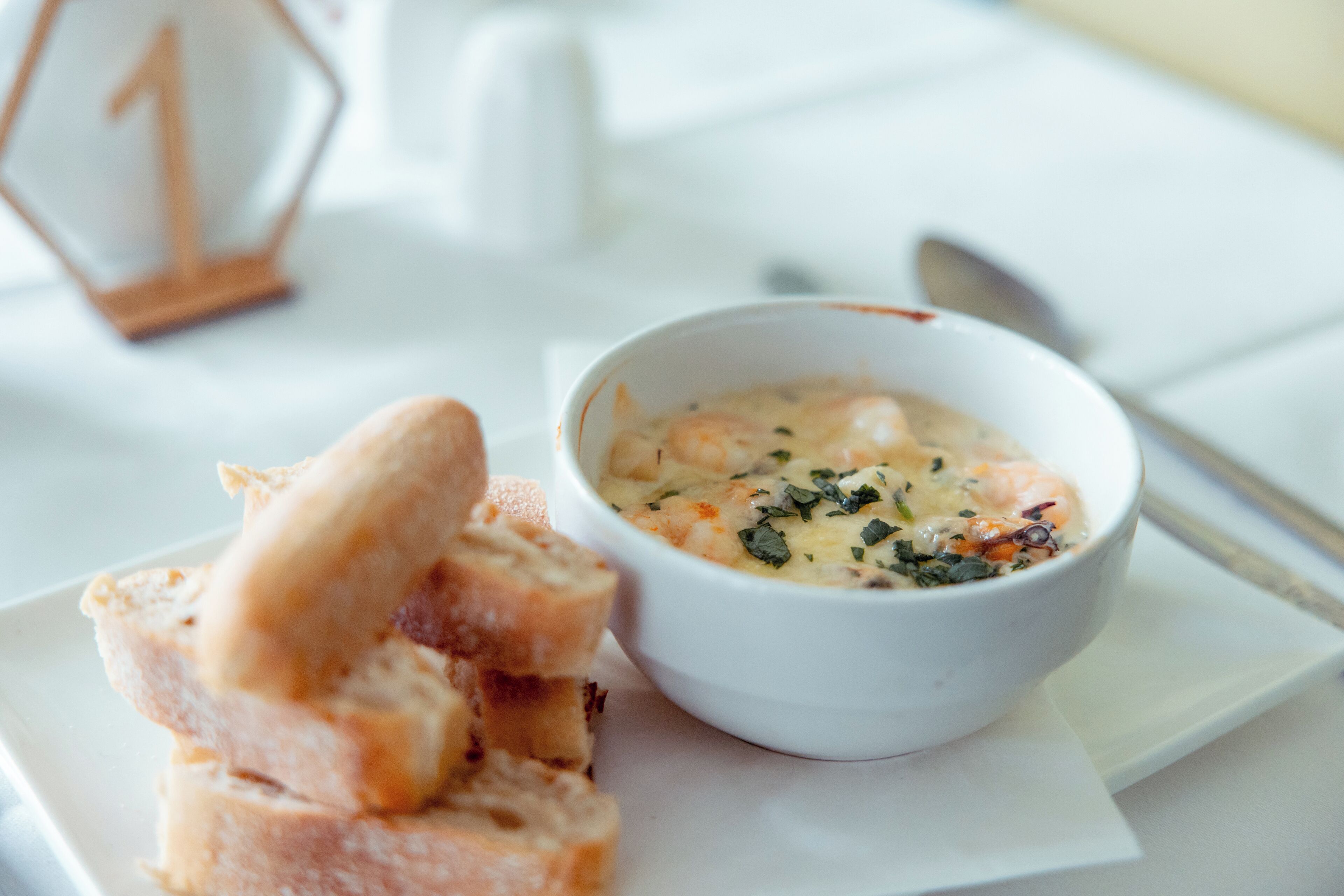 Ein weißer Tisch mit einer Schüssel Suppe und Brotscheiben.