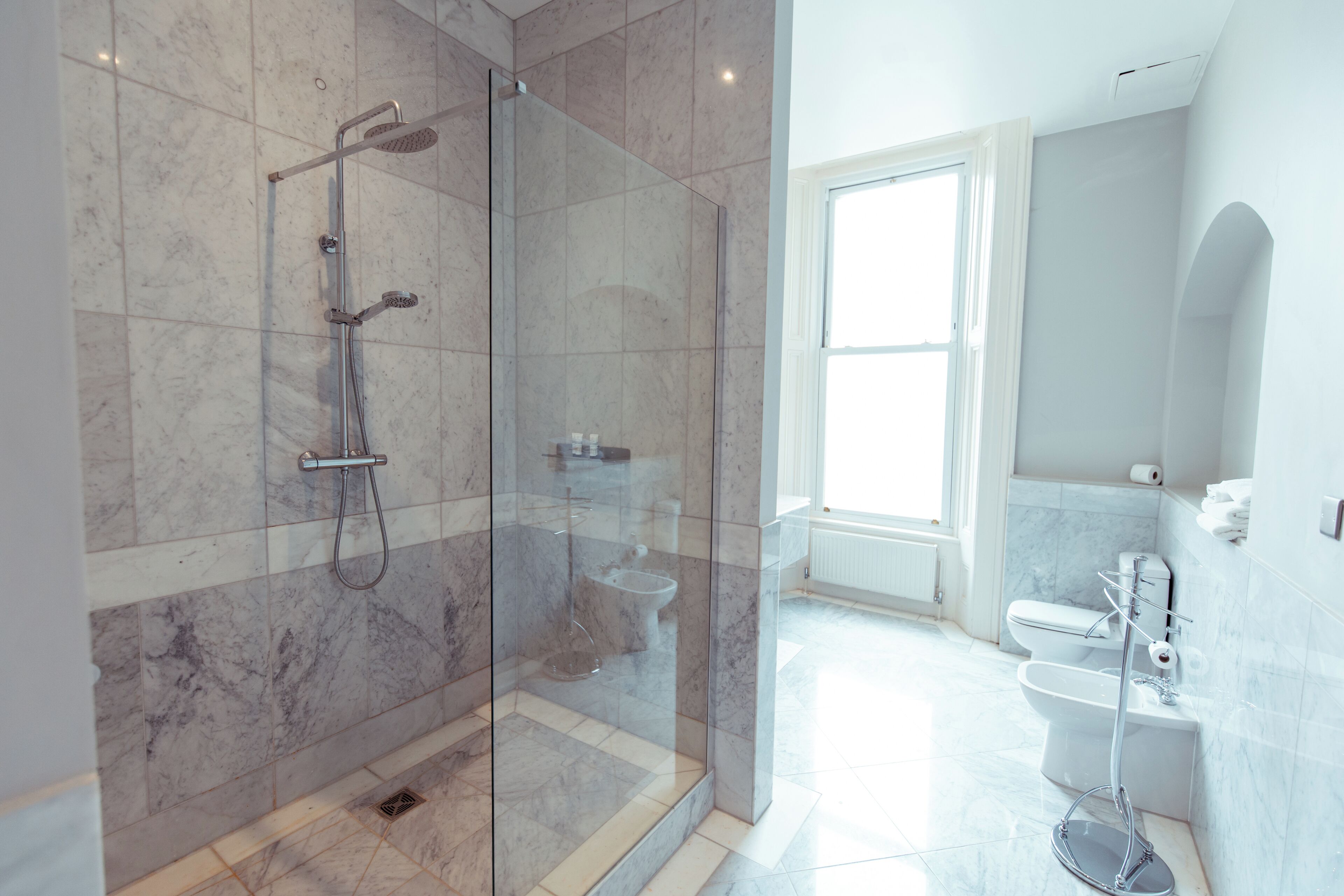 Une salle de bain moderne dotée d’une douche à parois de verre, de toilettes et d’un bidet.