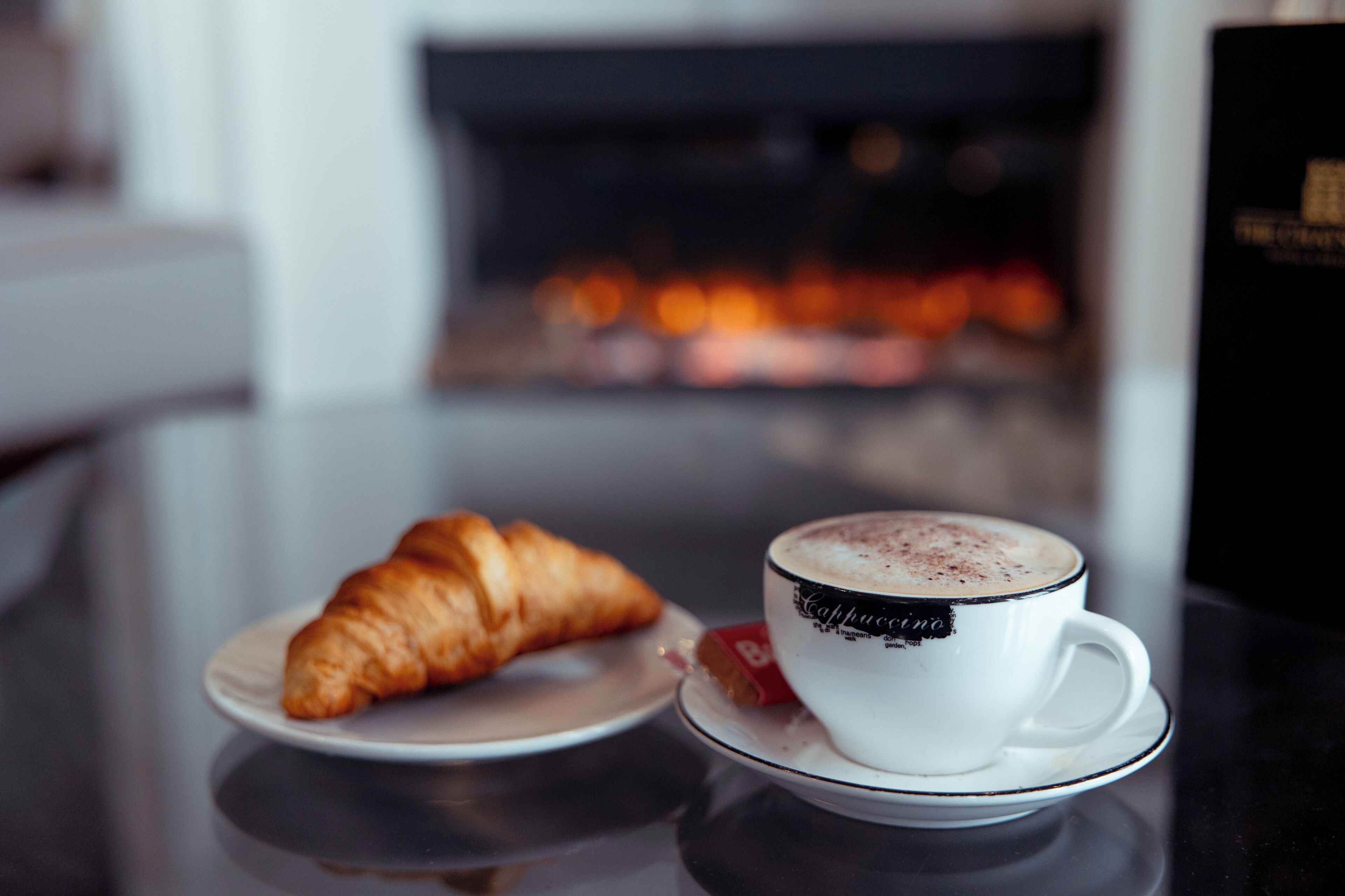 A croissant and a cup of coffee on a table with a blurred background.