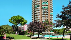 Un grand hôtel doté de nombreux balcons, entouré de verdure et comprenant une piscine.