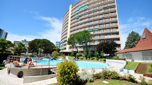 Un immeuble de grande hauteur avec une piscine en premier plan.
