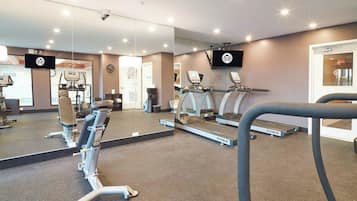 A gym with exercise equipment, mirrors, and a television.