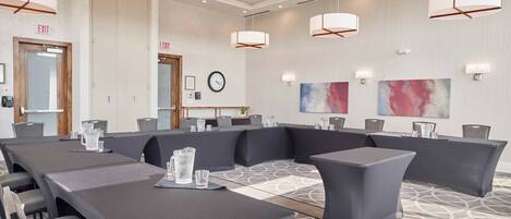A conference room with a large table, multiple chairs, and a clock on the wall.