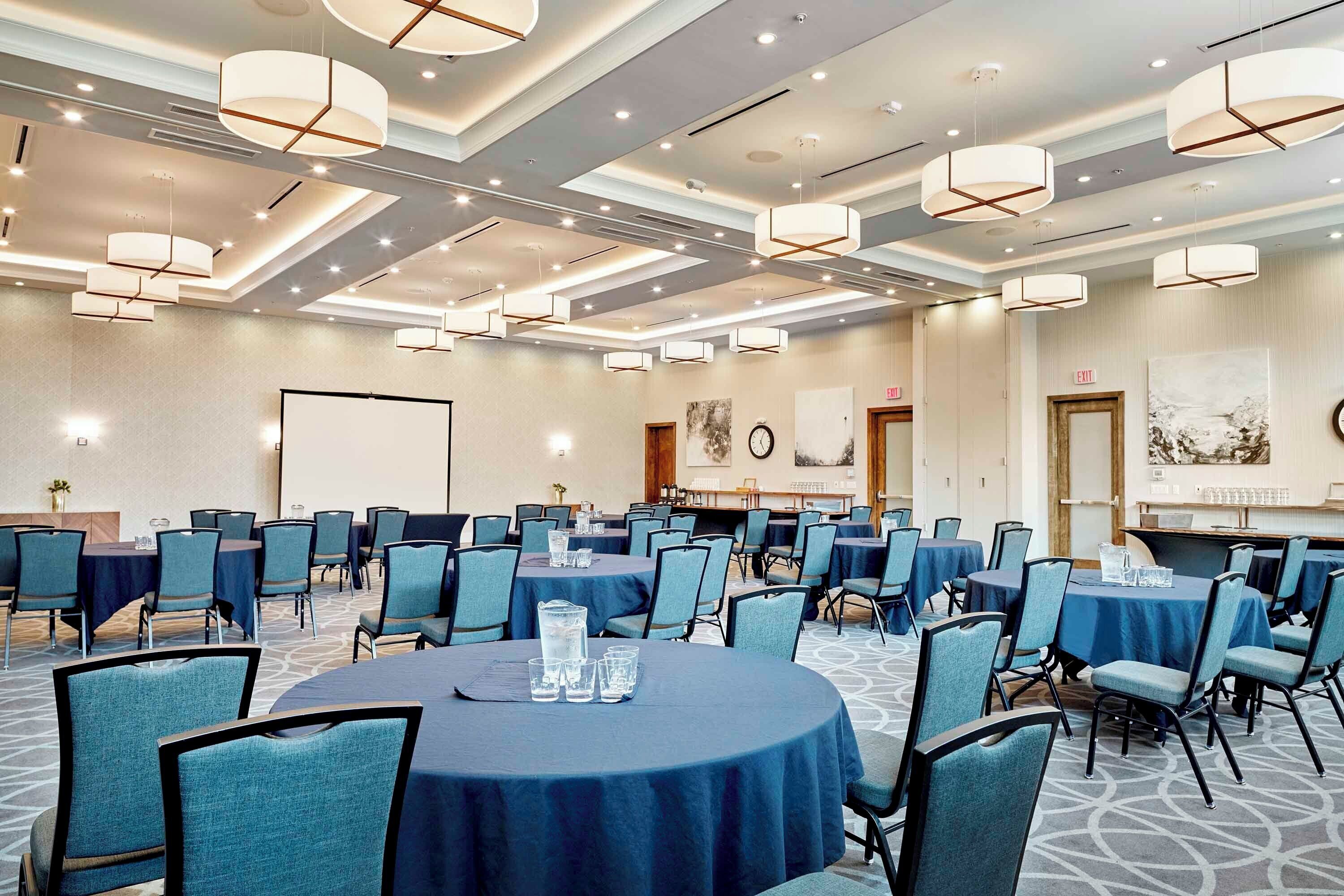 A conference room with round tables, chairs, and overhead lighting.
