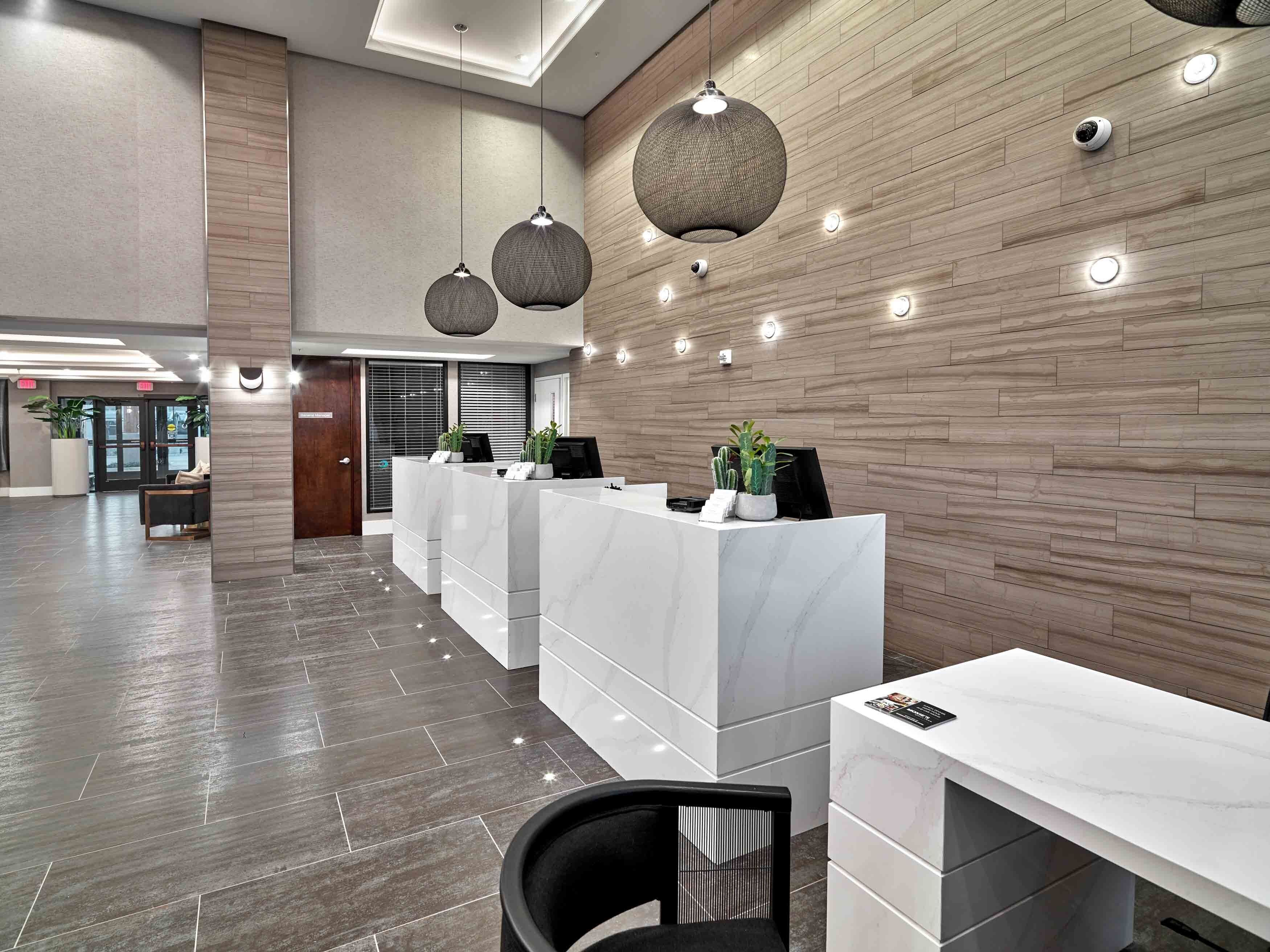 A modern reception area with marble counters, pendant lighting, and a wooden wall.