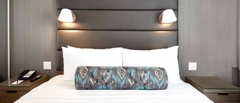 A hotel room with a large bed, two bedside lamps, a phone, and a nightstand.