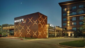 A modern building with 'MOXIE'S GRILL BAR' signage, featuring a geometric facade and a visible entrance. - Sandman Signature Plano - Frisco Hotel (Plano)