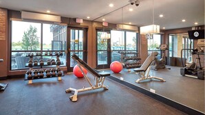 A gym with exercise equipment, large windows, and an exit sign. - Sandman Signature Plano - Frisco Hotel (Plano)
