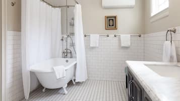 A bathroom with a white bathtub, a shower curtain, a framed picture on the wall, and a towel rack.
