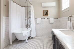 A bathroom with a white bathtub, a shower curtain, a framed picture on the wall, and a towel rack.