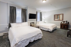 A hotel room with two beds, a flat-screen TV, a mirror, and a small wooden side table.