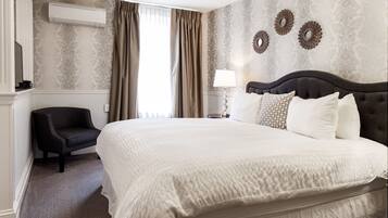 A hotel room with a large bed, a chair, a lamp, and decorative wall mirrors.