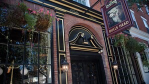 Un edificio de ladrillo con una puerta negra y un letrero que dice "BULLS HEAD".