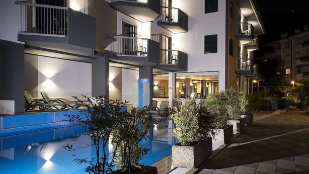 A modern hotel with a swimming pool, outdoor seating, and multiple balconies. - Villa Delle Rose (ARCO)