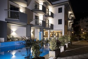 A modern hotel with a swimming pool, outdoor seating, and multiple balconies. - Villa Delle Rose (ARCO)