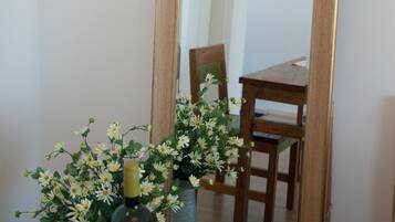 A mirror with a wooden frame, a bottle of wine, and a vase of flowers.