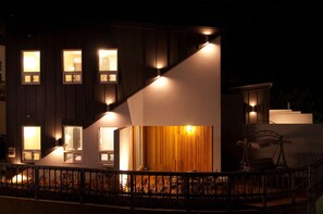 A modern building with multiple illuminated windows and a staircase leading to a second floor. - Grid 1398 Pension (Namhae)