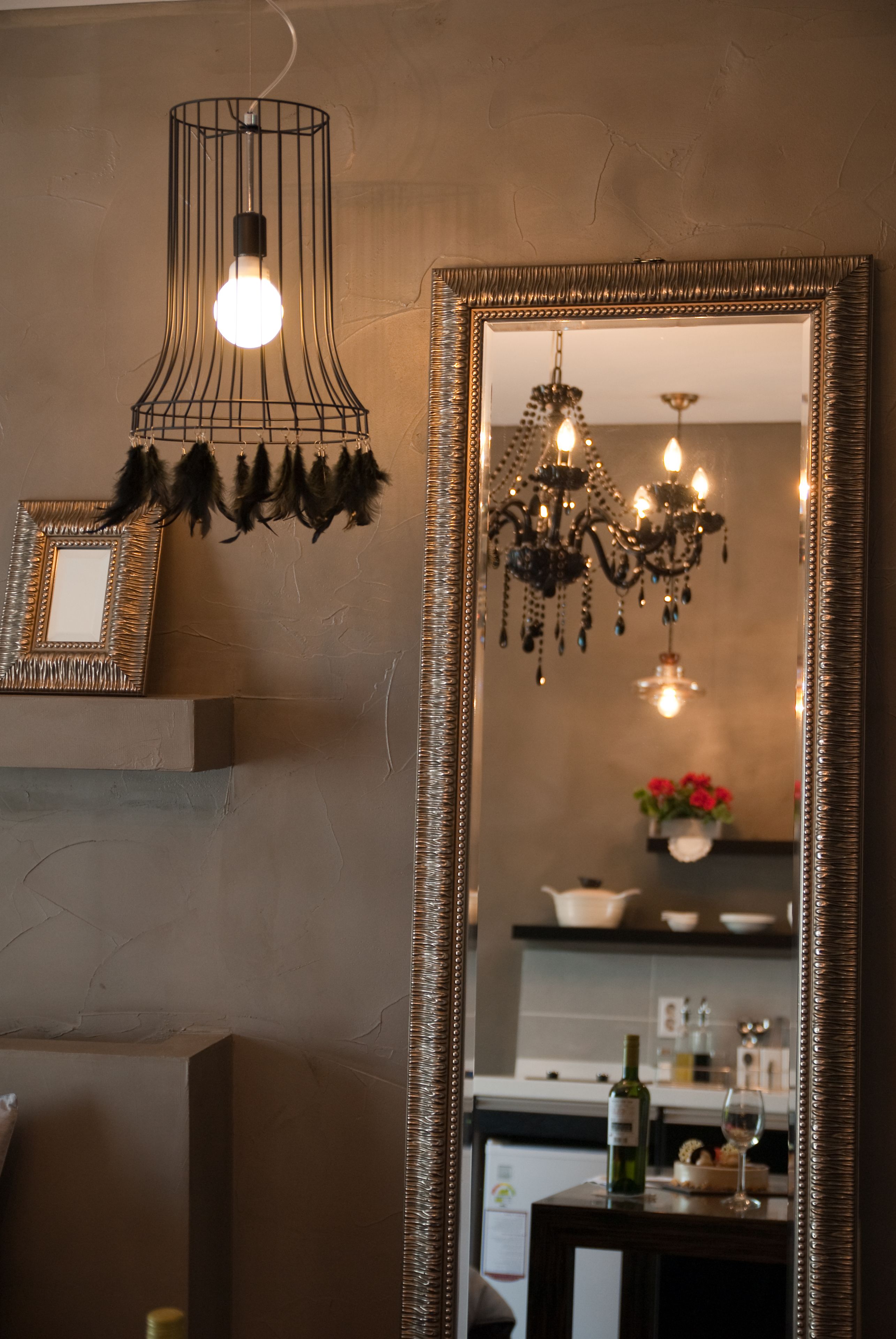 A room with a large mirror, a hanging light fixture, and a chandelier.