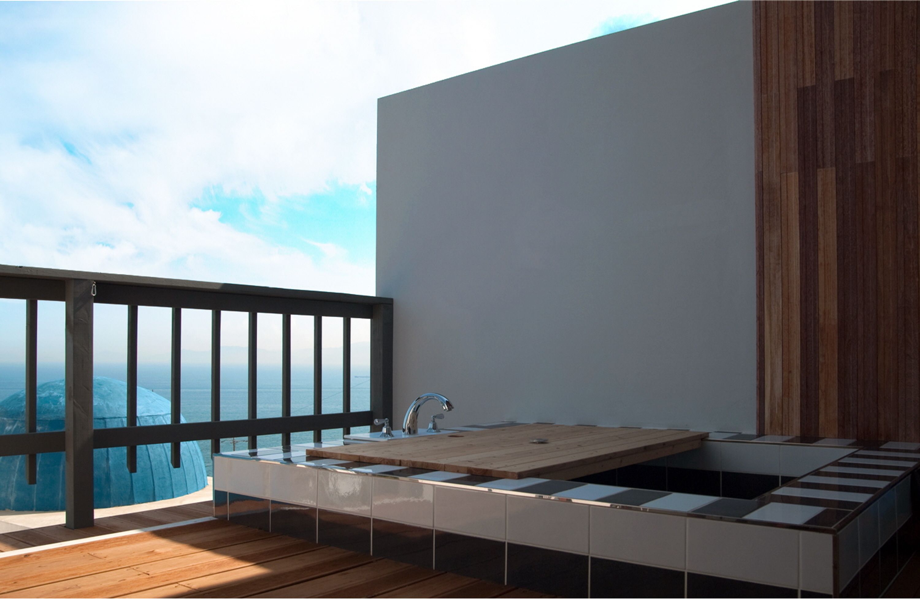 Een moderne badkamer met een groot bad, een houten terras en uitzicht op zee.