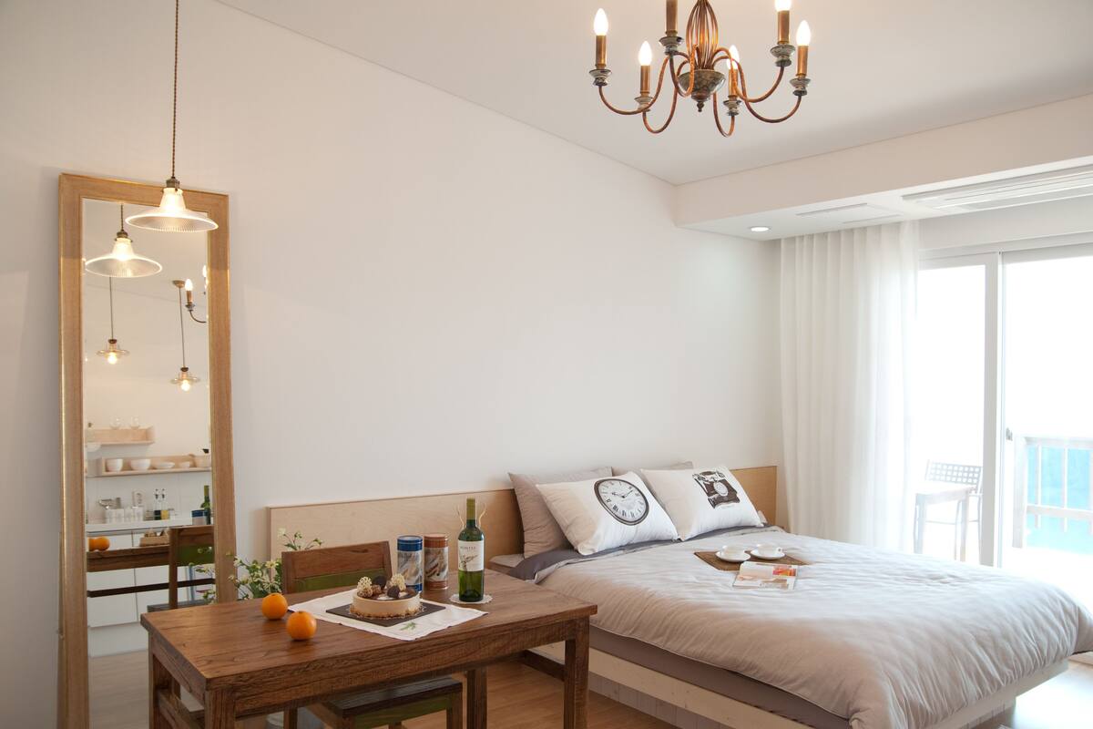 A bedroom with a bed, bedside table, and a mirror.