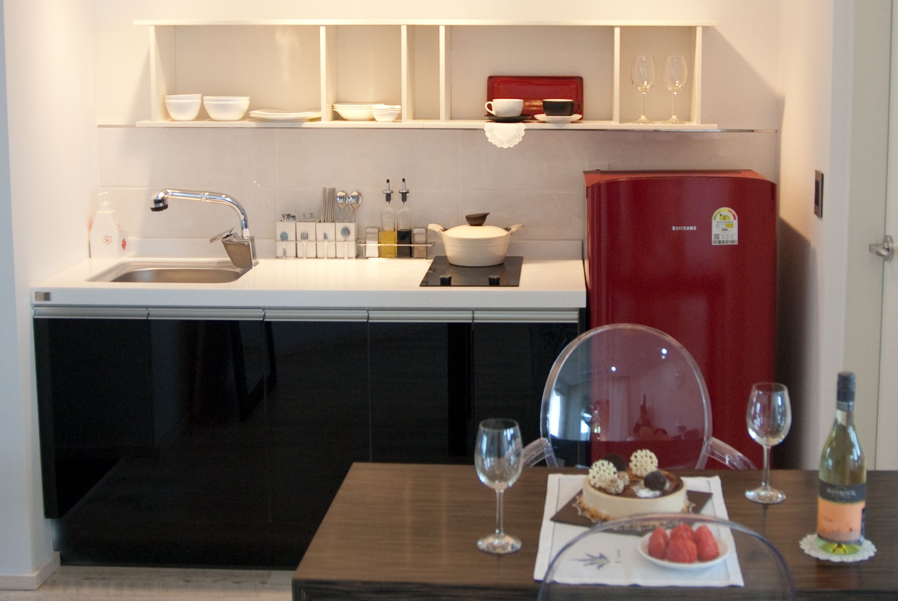 A compact kitchen with a sink, a refrigerator, and a dining area with a table set for two.