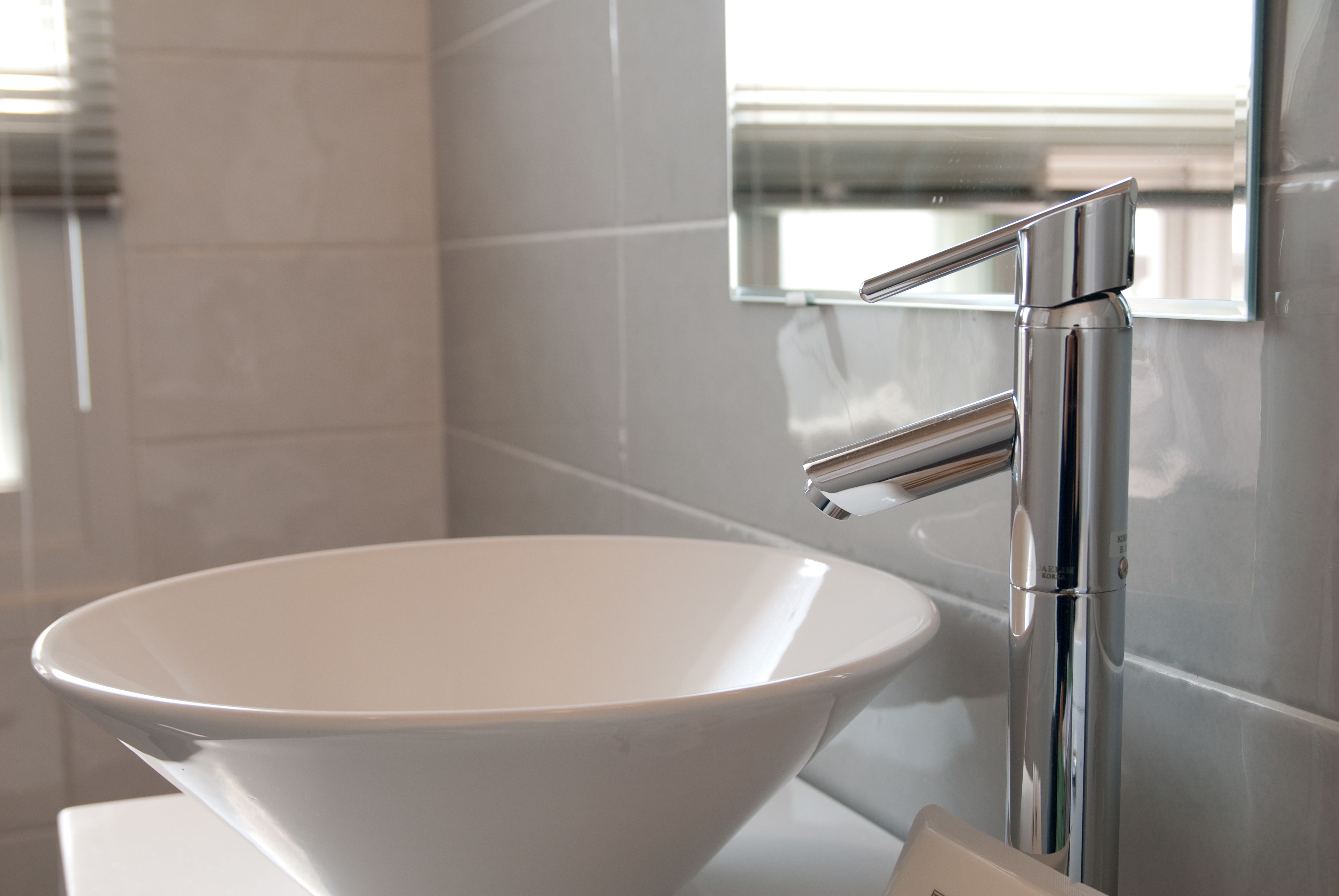 A modern bathroom with a white sink and chrome faucet.