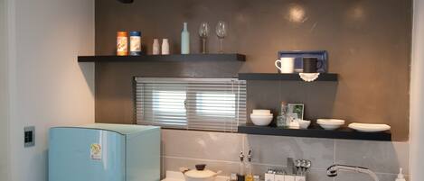 A modern kitchen with a light blue refrigerator, a built-in stove, a sink, and overhead lighting.