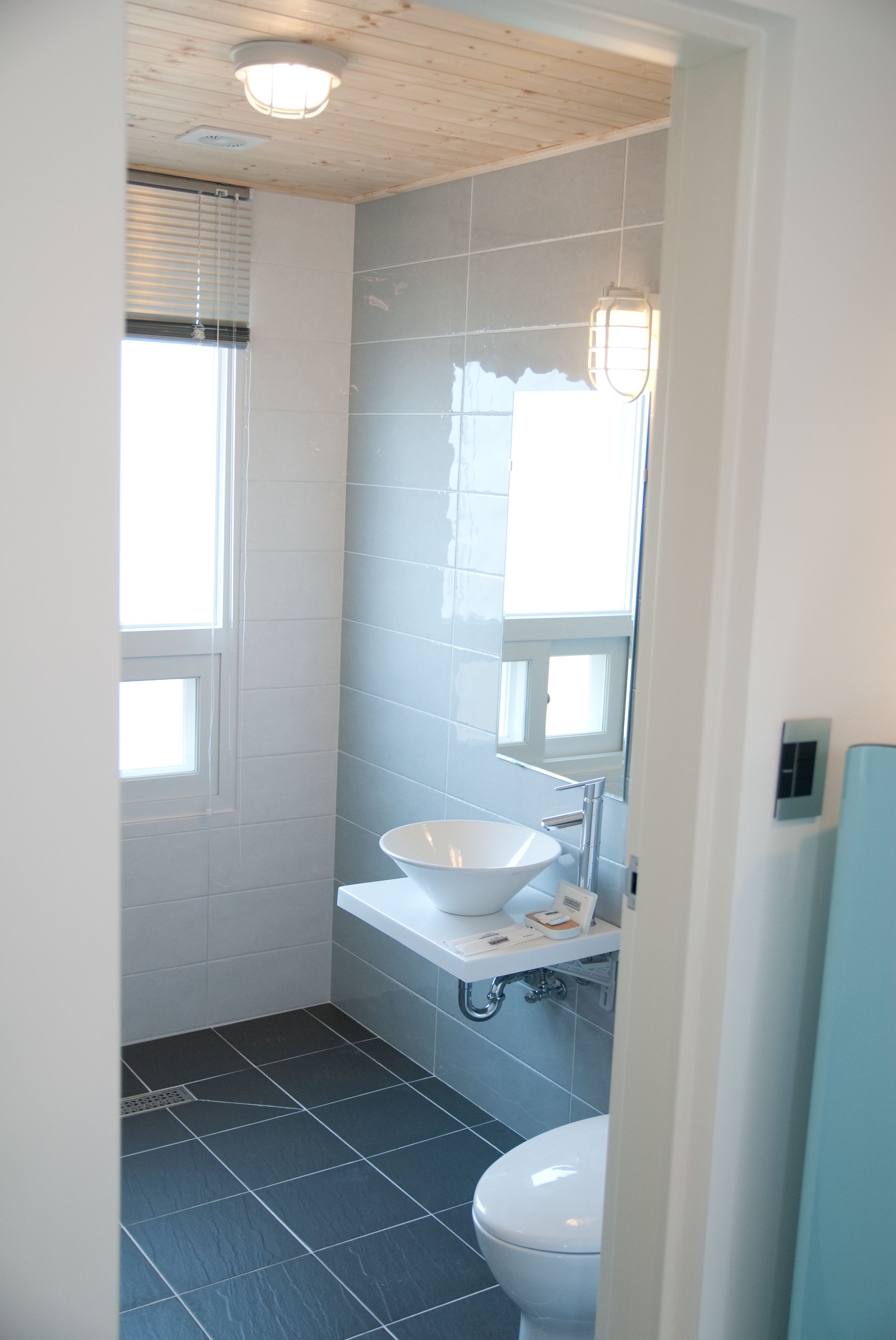 A bathroom with a white sink, a toilet, and a window with blinds.