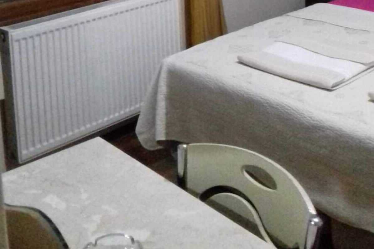 Una habitación de hotel con cama, ventana con cortinas, un radiador y una silla.