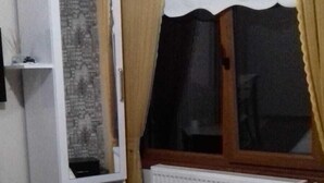 A bedroom with a bed, a wardrobe, a radiator, and a window with curtains. - Abant Hayalim Pansiyon (Bolu)