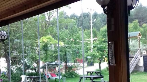 An outdoor dining area with tables and chairs, a view of a garden with trees and a picnic table. - Abant Hayalim Pansiyon (Bolu)