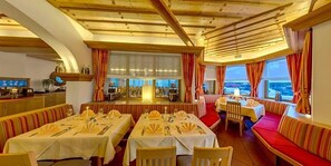 A restaurant with tables set for dining, a bar area, and a view of the sea. - Almhotel Karnten (Hermagor-Pressegger See)