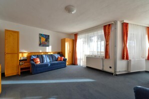 A room with a blue sofa, wooden cabinet, and a radiator. - Almhotel Karnten (Hermagor-Pressegger See)