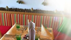 A table set for four with a striped cushion, a menu, and a small vase of flowers. - Almhotel Karnten (Hermagor-Pressegger See)