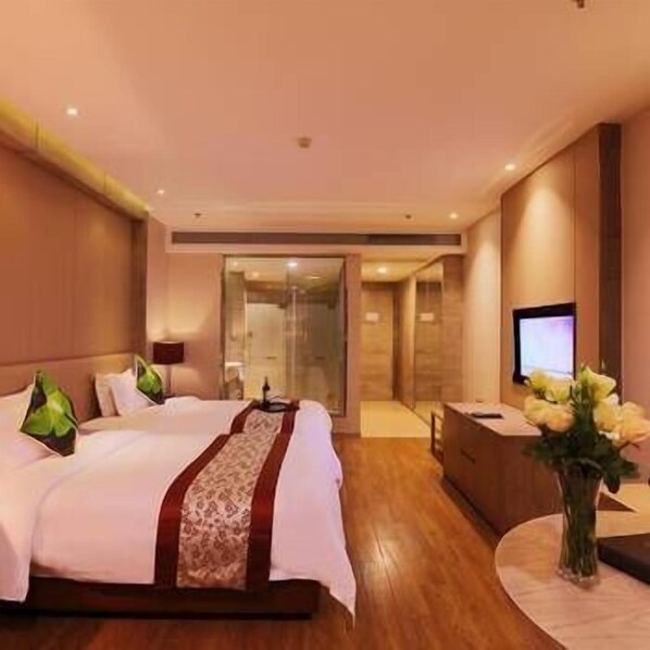 A hotel room with a bed, a desk, a TV, and a vase of flowers. - Wan Yue Hotel (Suzhou)