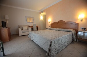 Habitación de hotel con una cama grande, un sofá, un escritorio y un espejo.
