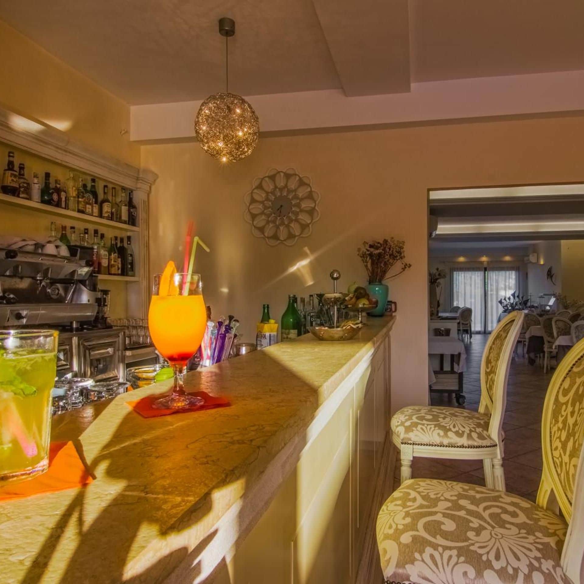 Eine Bar mit einer Theke, Barhocker und einer dekorativen Pendelleuchte.
