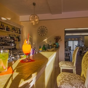 Una zona de bar con mostrador, taburetes y una lámpara colgante decorativa.