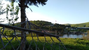 A rope bridge over a river with a flag on a hill in the background. - Tas Konak Butik Otel (Aybasti)