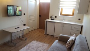A compact living space with a kitchenette, a sofa, a TV, and a small dining table. - Tas Konak Butik Otel (Aybasti)