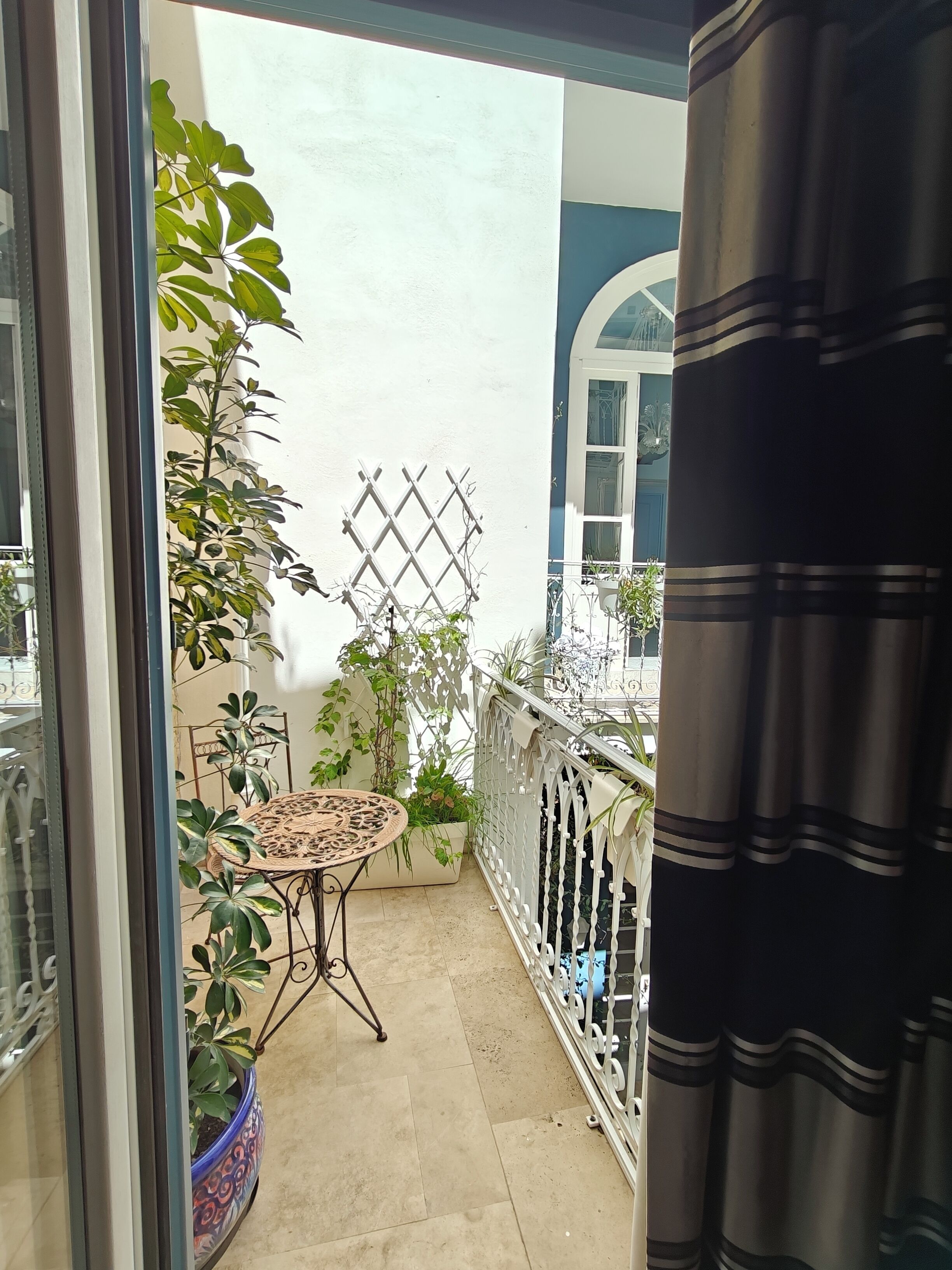 A balcony with potted plants, a small table, and a white lattice fence.