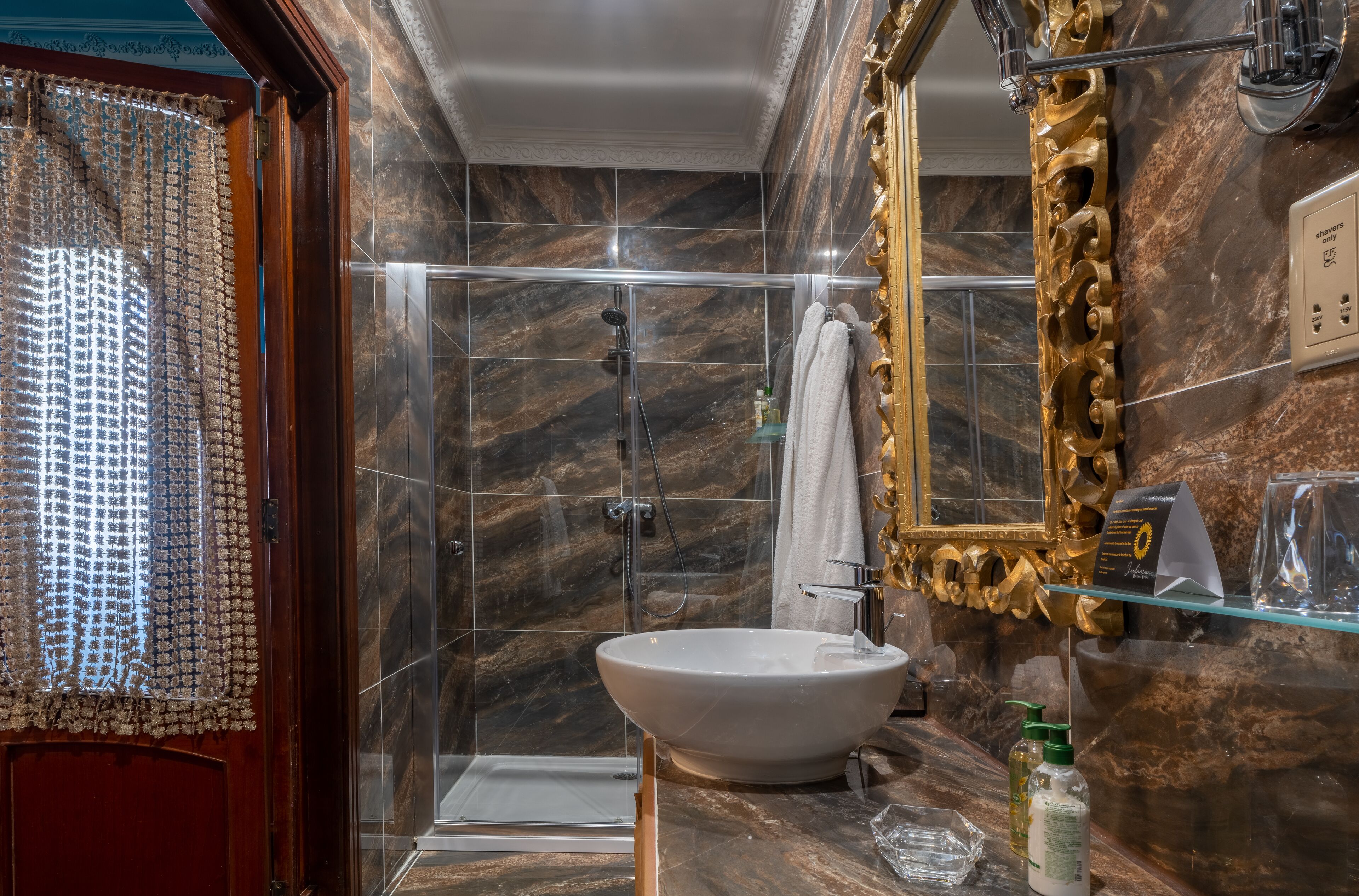 Een badkamer met een groot wastafel, douche en een decoratieve spiegel.