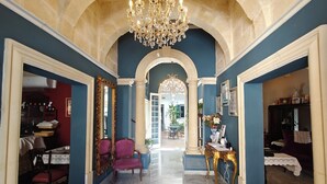 A grand hallway with a chandelier, marble floor, and classical architecture. - Julina Boutique Living (Mosta)