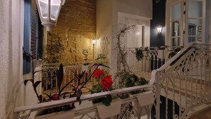 A balcony with a stone wall, metal railing, and potted plants. - Julina Boutique Living (Mosta)