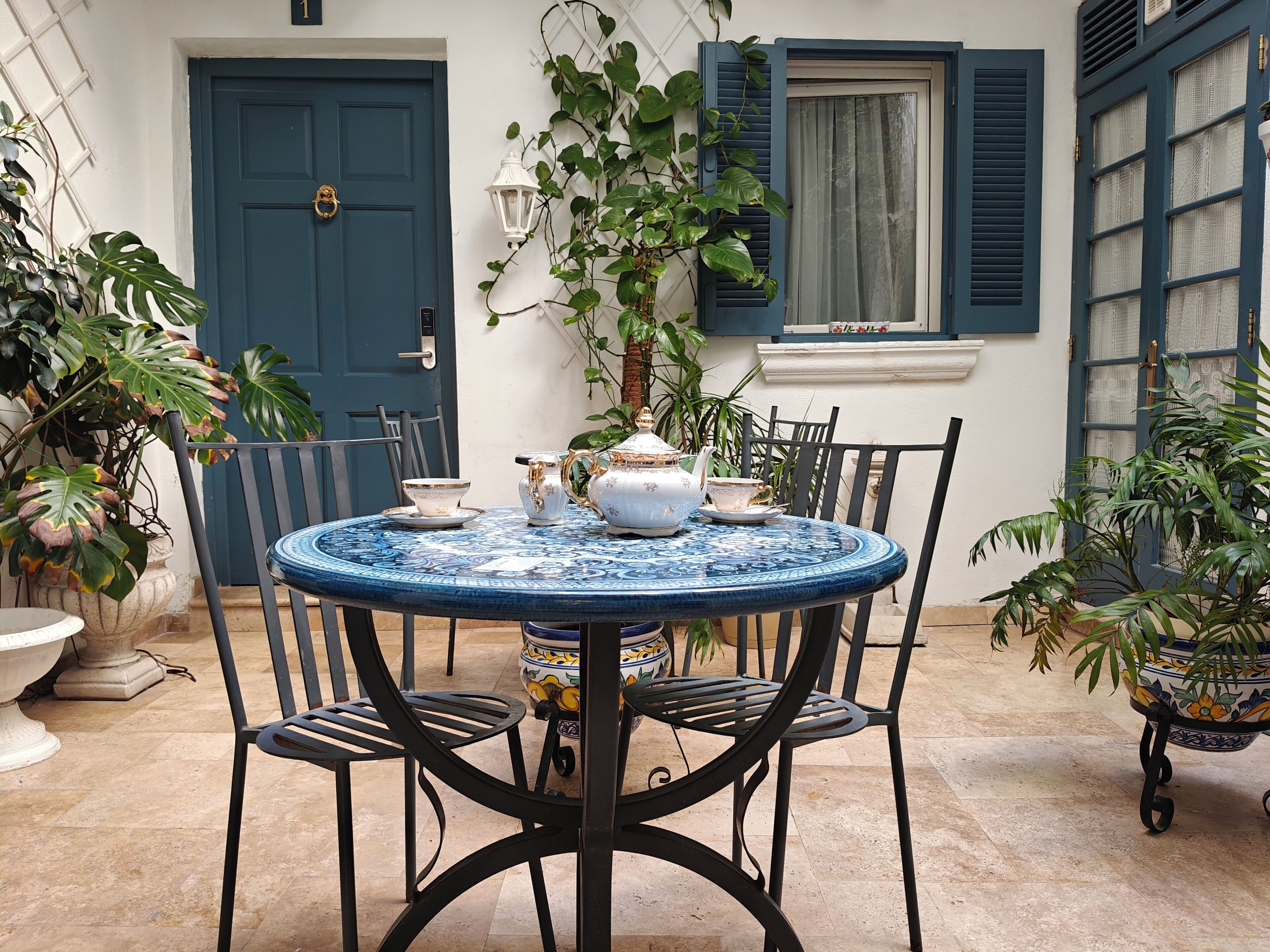 A round table with chairs, a door, and potted plants.