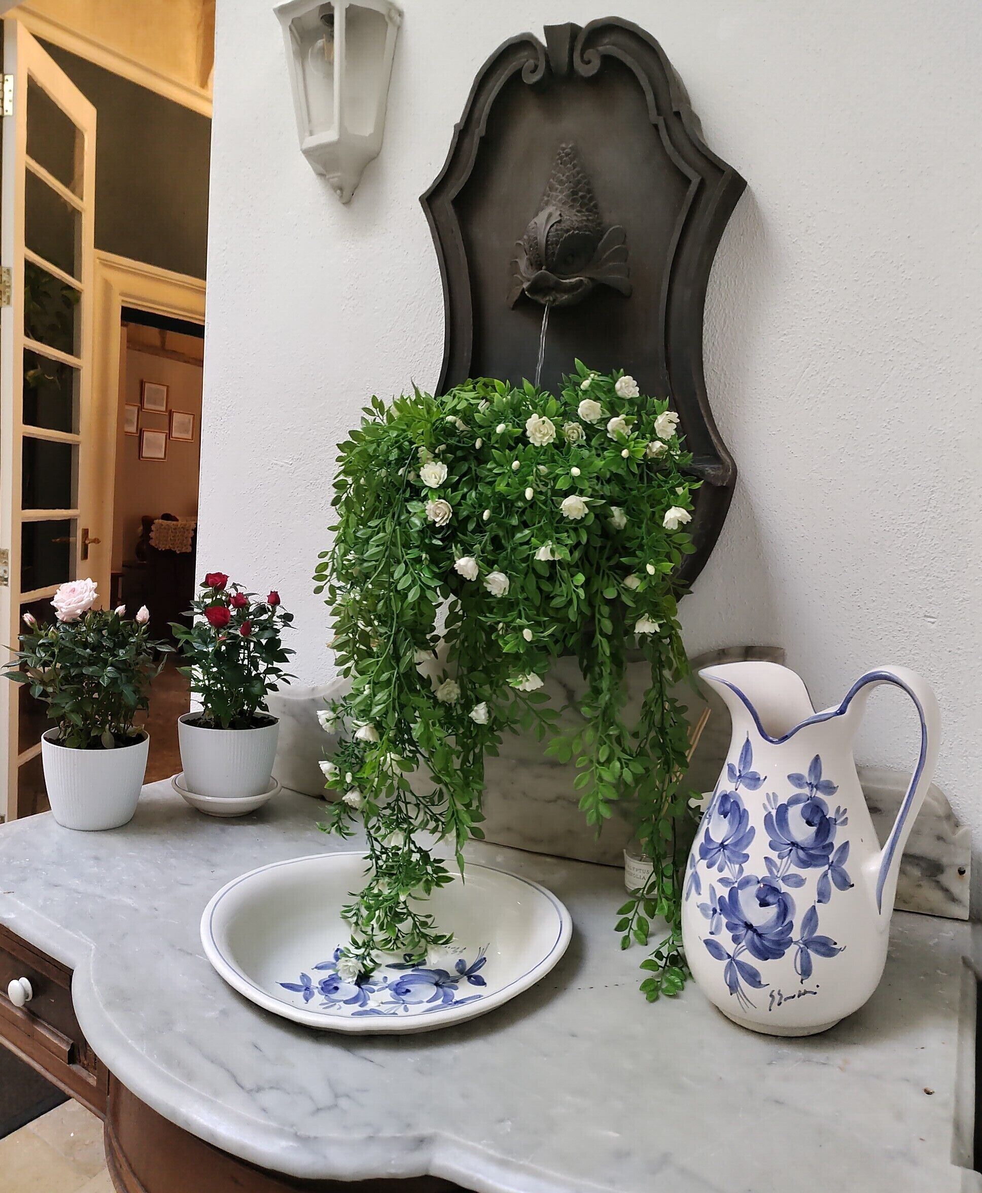 A marble countertop with a white plate, a blue and white pitcher, and potted plants.