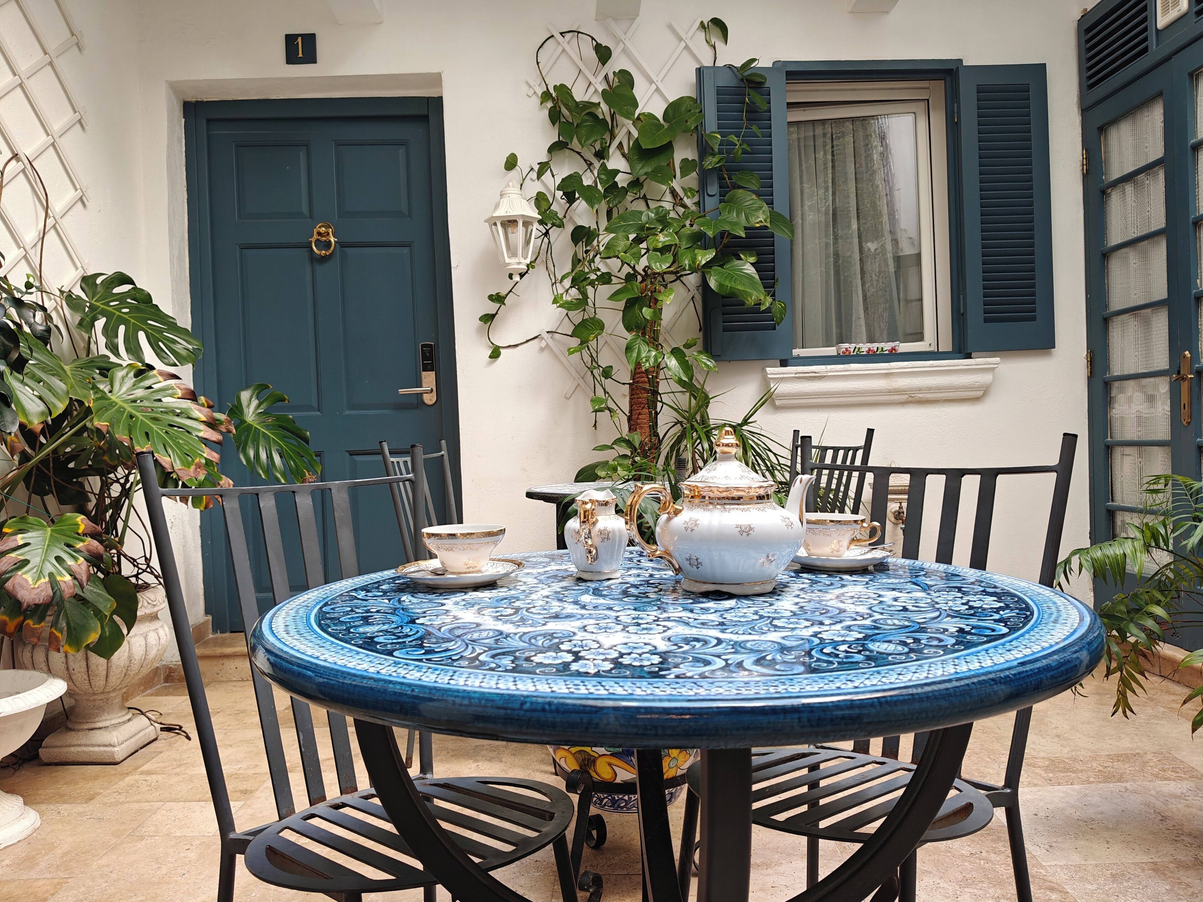 A round table with a blue and white patterned tablecloth, surrounded by black chairs.